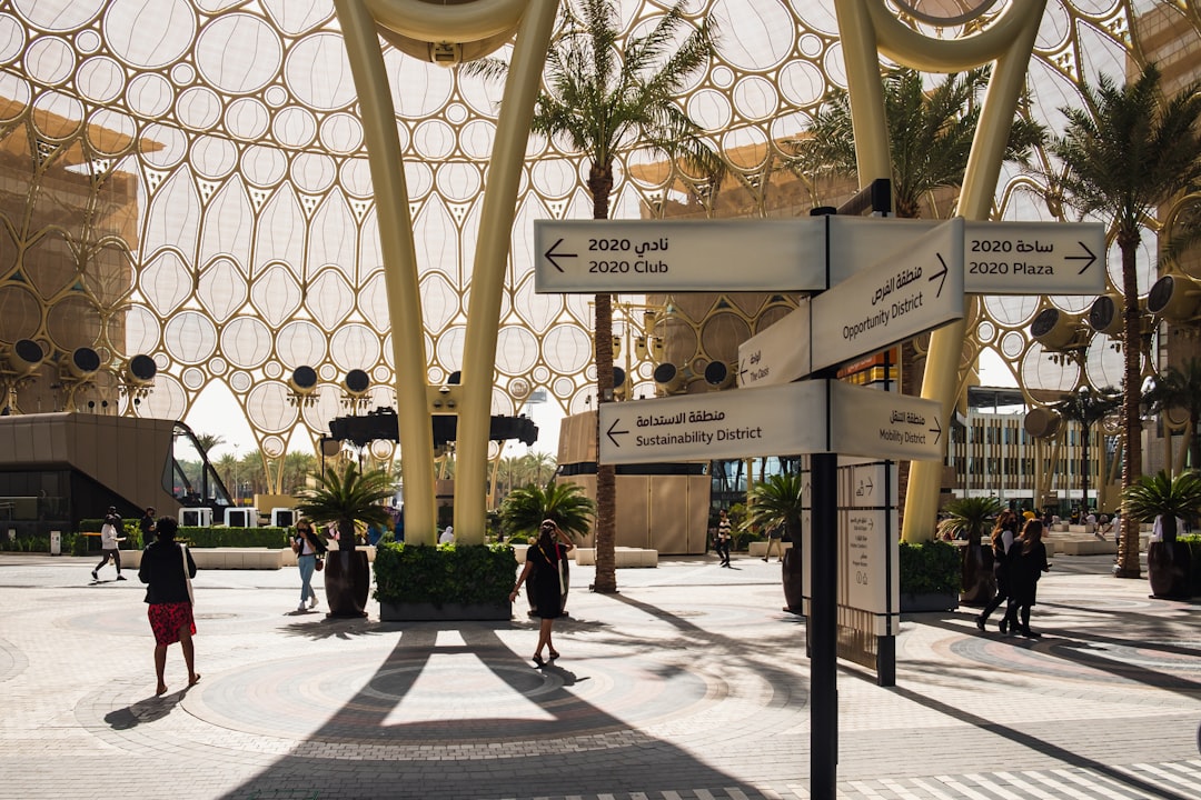 Families and children exploring a lush zoo in Dubai, walking past animal enclosures on a sunny day