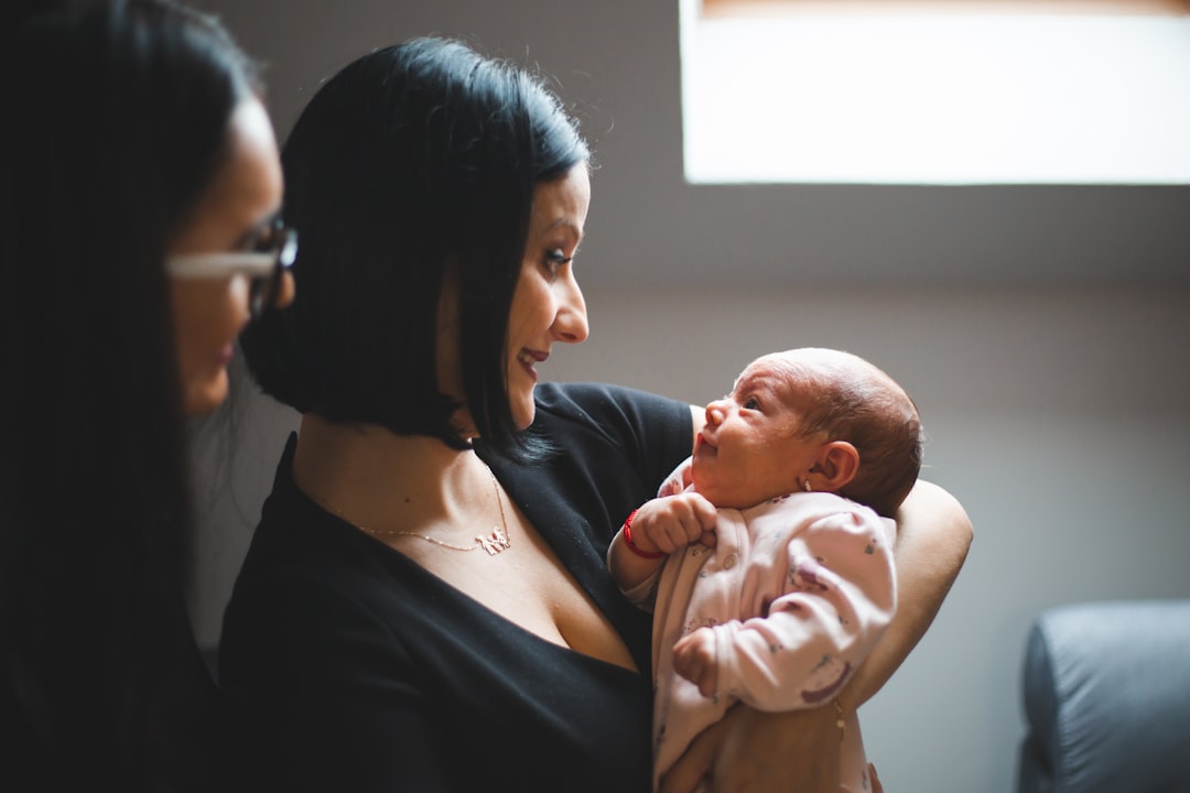 A new mother at home holding her newborn, looking calm and supported, warm and authentic