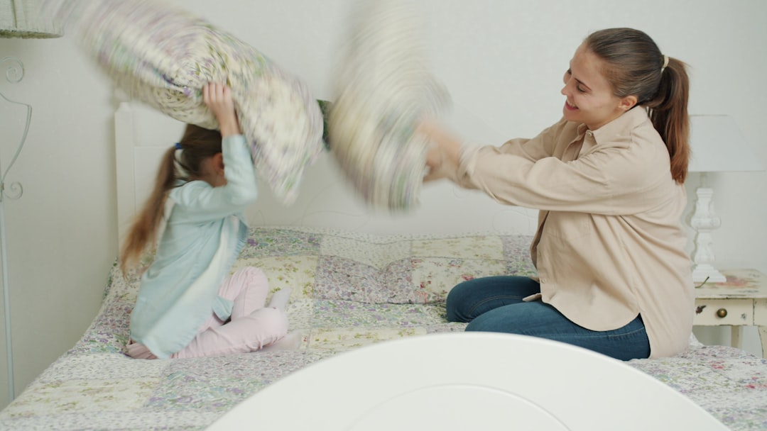 A joyful new mother lifting her baby up in the air, both smiling, in a warm and bright home setting