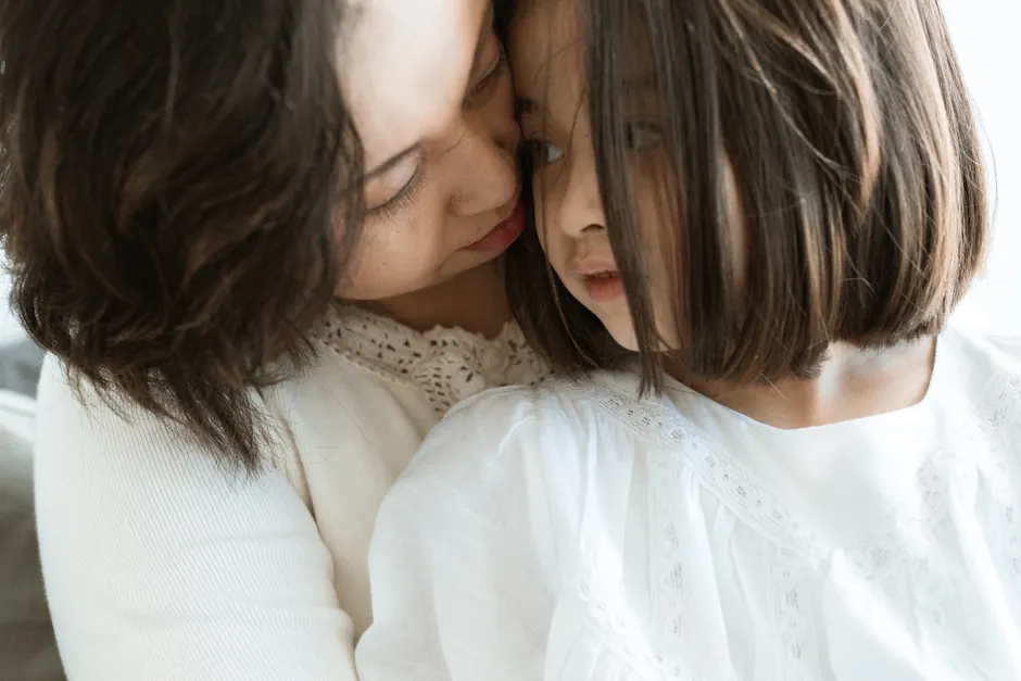 A mother sitting quietly with her eyes closed, looking calm and supported in a softly lit room