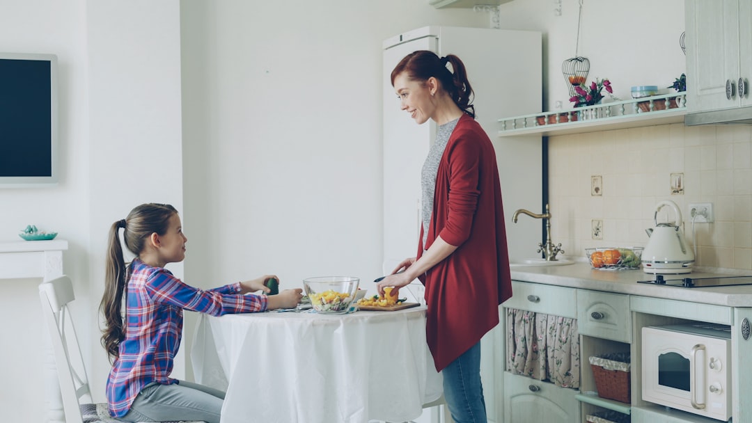 A new mother eating a warm, nourishing home-cooked meal at a kitchen table, looking replenished