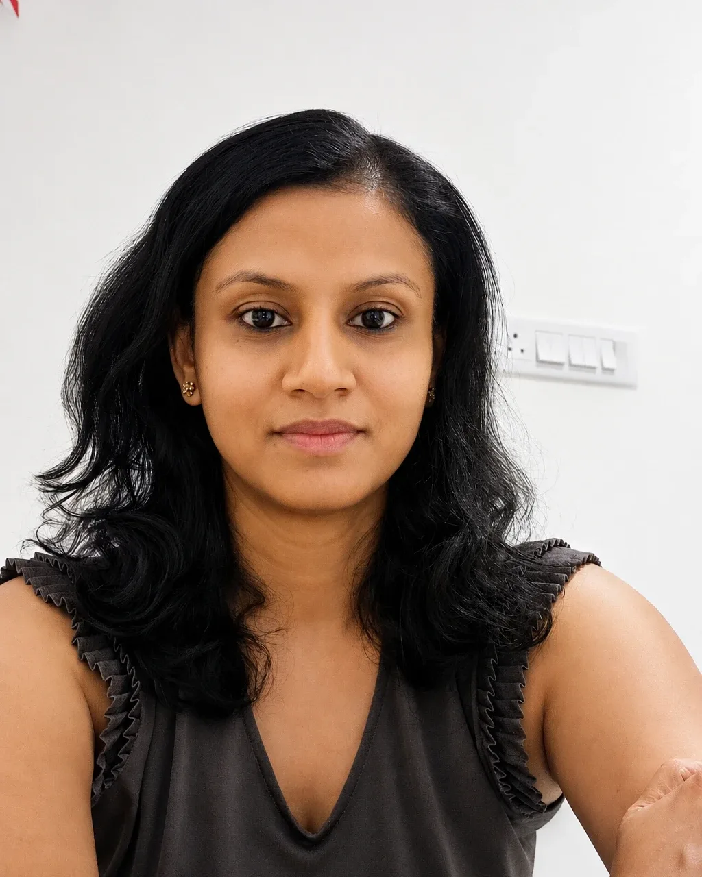 Renuka Kirane, prenatal yoga teacher, in a calm studio setting, warm and approachable professional portrait