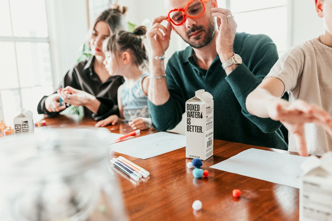 A small group of people gathered around a table with homeopathic books and remedy bottles, engaged in an attentive discussion