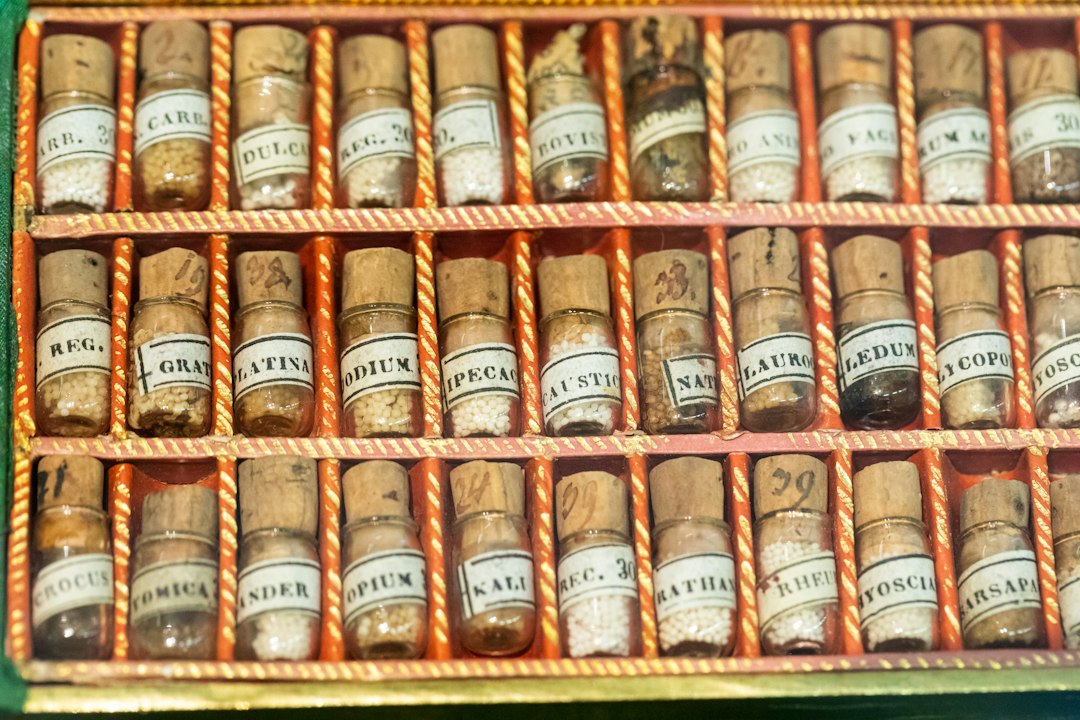 A neatly arranged set of small labeled homeopathic remedy vials and a printed case card on a wooden surface