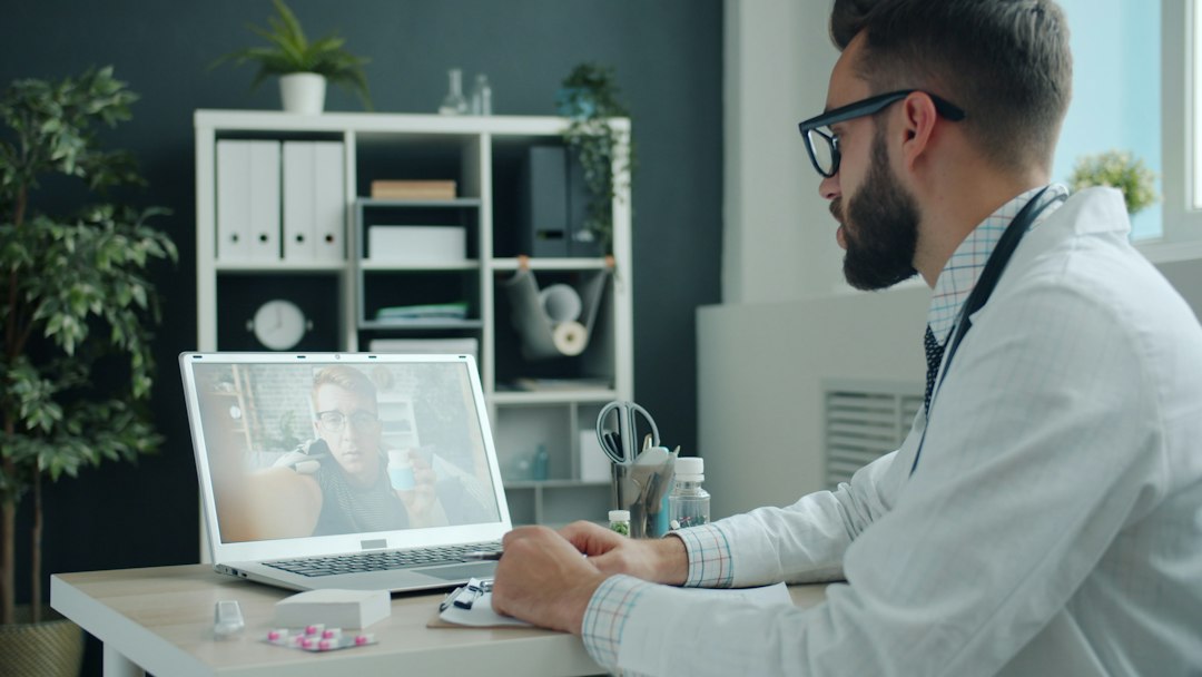 A person speaking with a doctor over a video call on a laptop at home, looking attentive and at ease